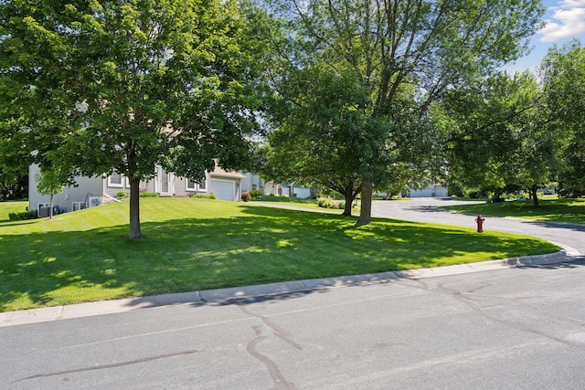view of property hidden behind natural elements with an attached garage and a front yard