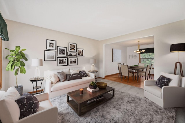 living room with baseboards, wood finished floors, and a notable chandelier