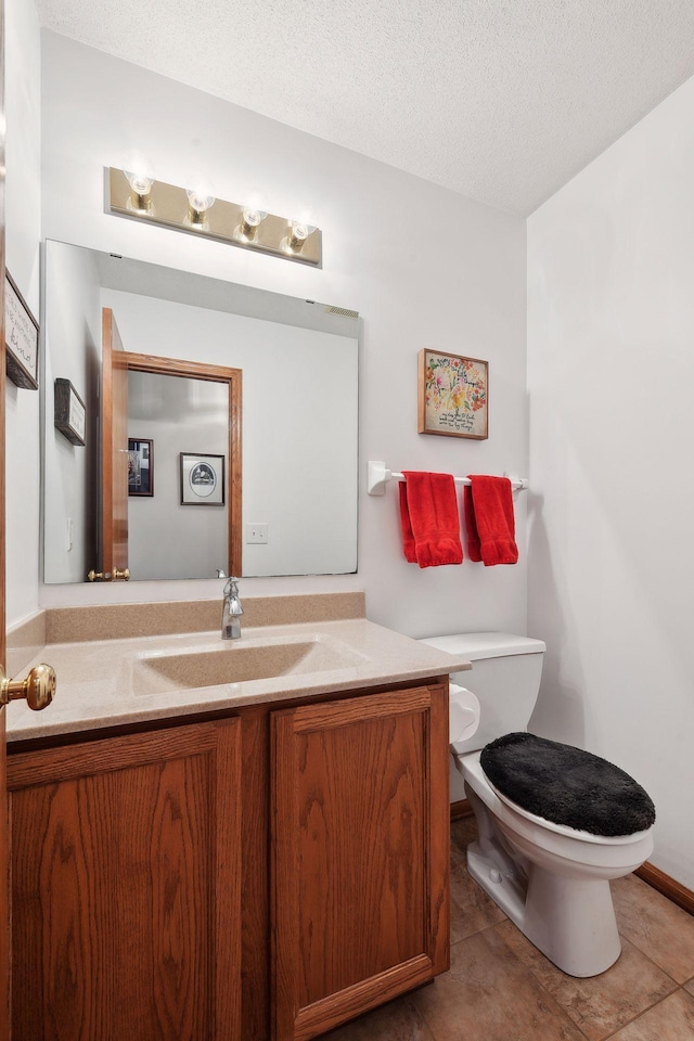 bathroom with vanity, tile patterned flooring, toilet, and a textured ceiling