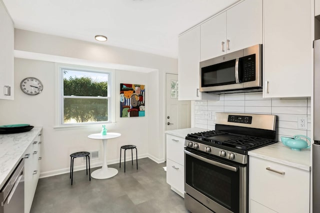 kitchen with light stone countertops, white cabinetry, decorative backsplash, appliances with stainless steel finishes, and baseboards