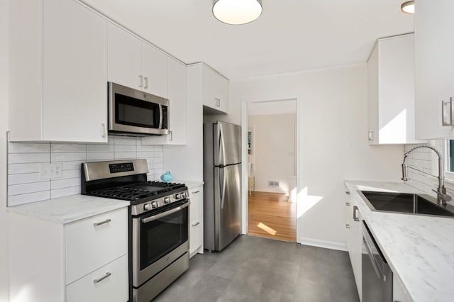 kitchen with tasteful backsplash, white cabinetry, stainless steel appliances, and a sink