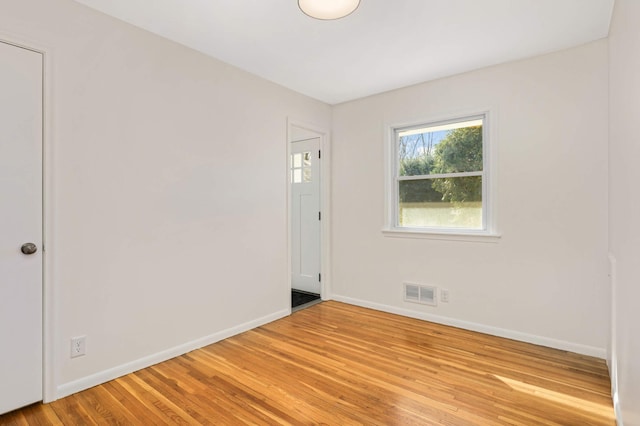 unfurnished room with baseboards, light wood-type flooring, and visible vents
