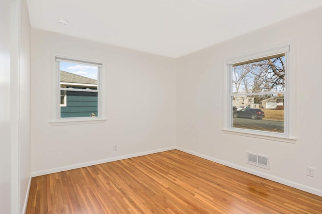 unfurnished room with baseboards, visible vents, light wood-style flooring, and plenty of natural light