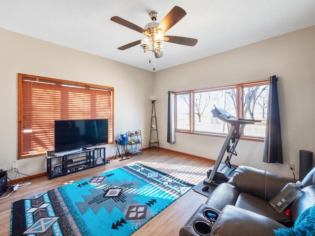 living area with baseboards, wood finished floors, and ceiling fan