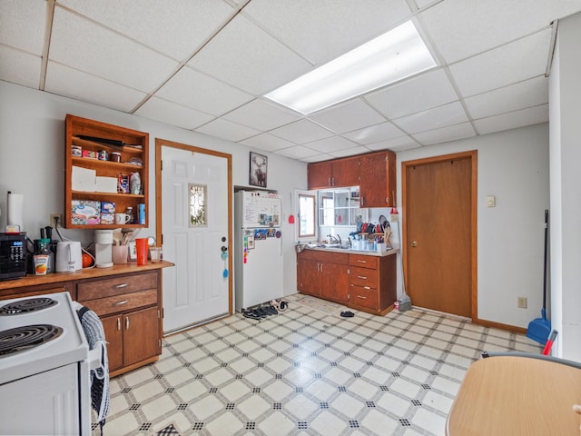 kitchen featuring a drop ceiling, light floors, light countertops, white appliances, and brown cabinetry