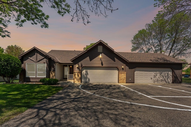 ranch-style home featuring driveway, a garage, a front lawn, and roof with shingles