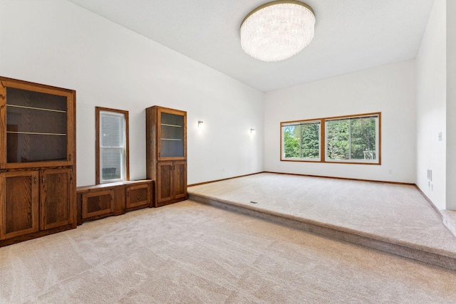 spare room featuring light carpet and baseboards