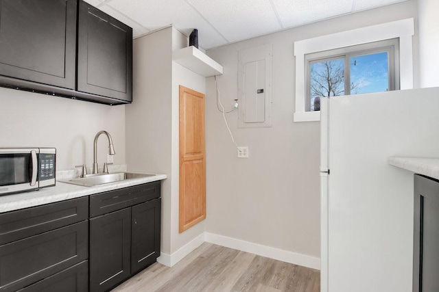 kitchen with stainless steel microwave, a sink, light wood finished floors, and light countertops