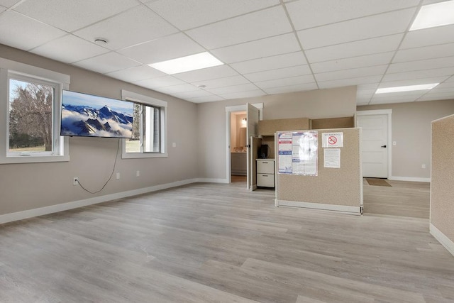 spare room featuring baseboards, light wood-style floors, and a paneled ceiling