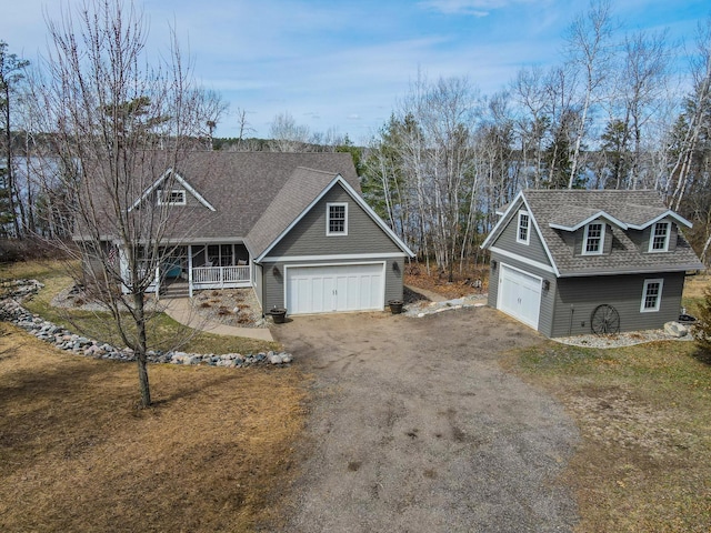 view of front of house with driveway, a garage, covered porch, and a shingled roof