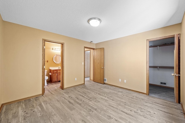 17813 224th Ave NW, Big Lake, MN 55309 - unfurnished bedroom featuring wood finished floors, baseboards, a walk in closet, and ensuite bathroom
