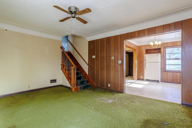 123 Thomas Hill Rd, Jackson, MN 56143 - unfurnished living room with baseboards, wood walls, ceiling fan with notable chandelier, and carpet