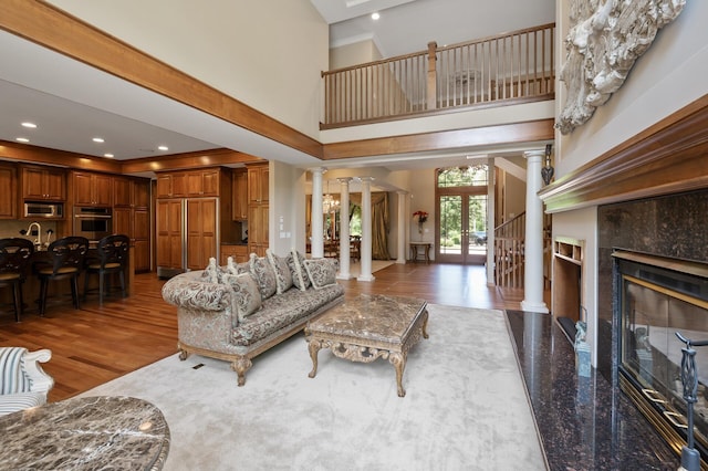 4325 Trillium Ln W, Minnetrista, MN 55364 - living area with ornate columns, a towering ceiling, a high end fireplace, and wood finished floors