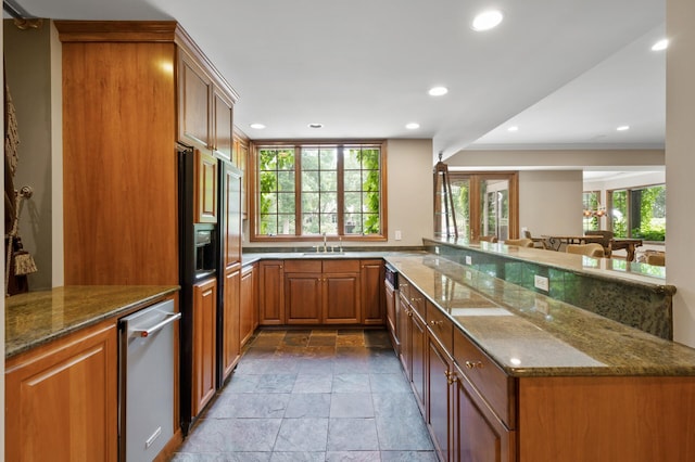 4325 Trillium Ln W, Minnetrista, MN 55364 - kitchen with stone tile flooring, brown cabinets, a peninsula, dark stone countertops, and recessed lighting