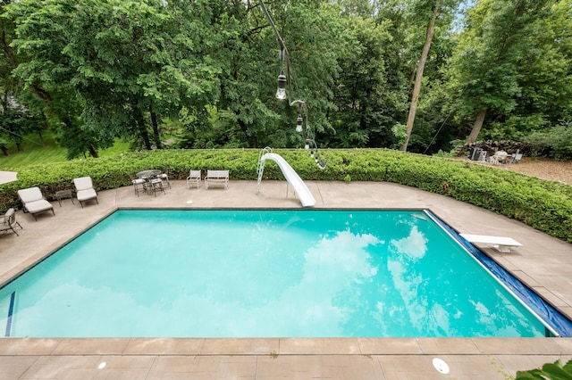 4325 Trillium Ln W, Minnetrista, MN 55364 - swimming pool featuring a water slide, a patio area, a diving board, and view of wooded area