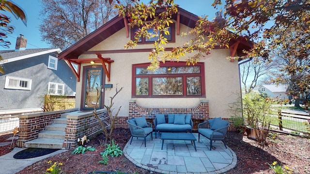 rear view of property featuring stucco siding, an outdoor hangout area, and fence