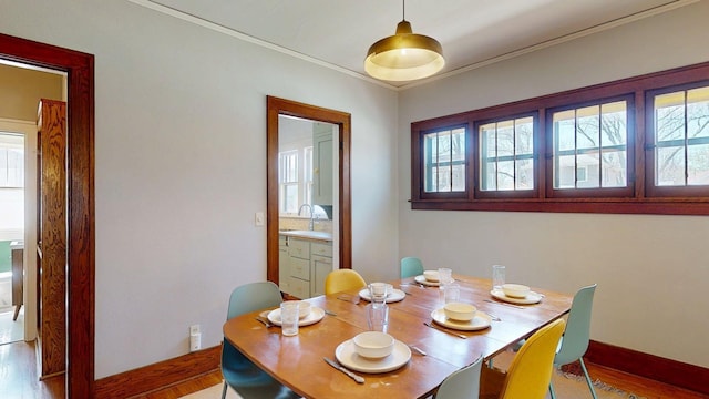 dining area featuring baseboards, ornamental molding, and wood finished floors