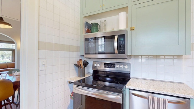 kitchen with tile walls, appliances with stainless steel finishes, decorative backsplash, and light stone counters