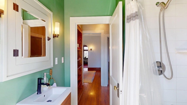 bathroom with a sink, tiled shower, and wood finished floors