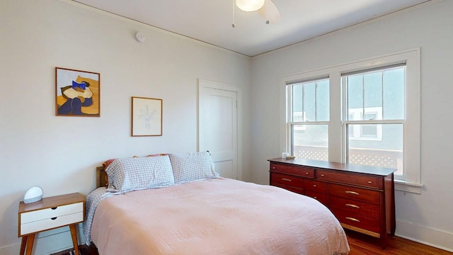 bedroom featuring a ceiling fan, baseboards, dark wood-style floors, and ornamental molding
