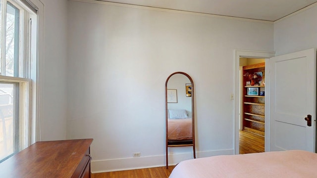 bedroom featuring baseboards, ornamental molding, and wood finished floors