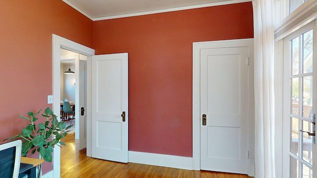 unfurnished bedroom featuring crown molding, baseboards, and wood finished floors