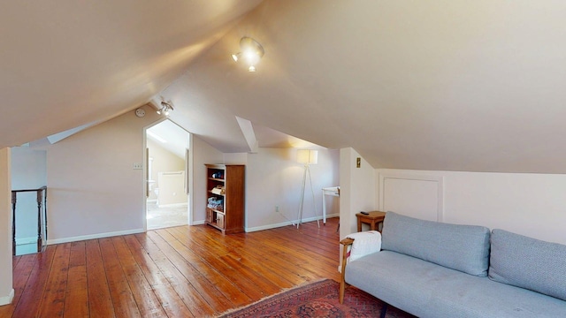 interior space featuring baseboards, lofted ceiling, and hardwood / wood-style flooring