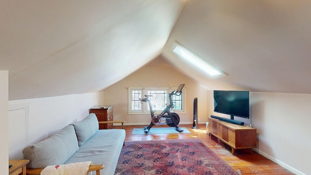 living room with baseboards, light wood finished floors, and lofted ceiling with skylight