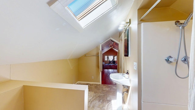 interior space with marble finish floor, lofted ceiling with skylight, and walk in shower