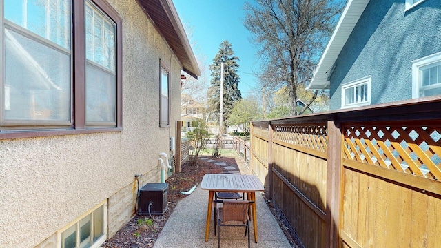 view of side of home with fence, central AC unit, a patio area, and stucco siding