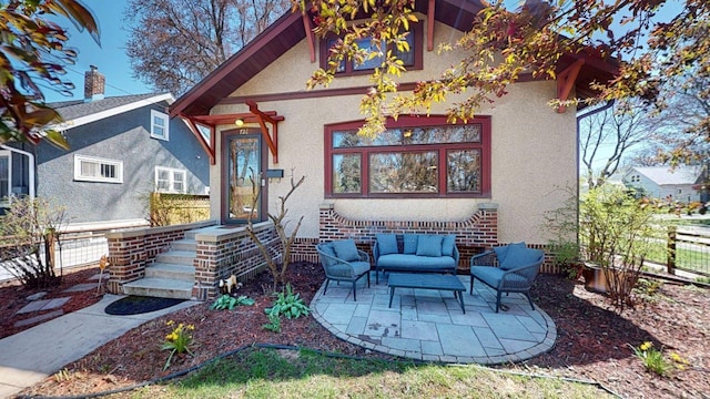 view of front facade with a patio area, stucco siding, an outdoor hangout area, and fence