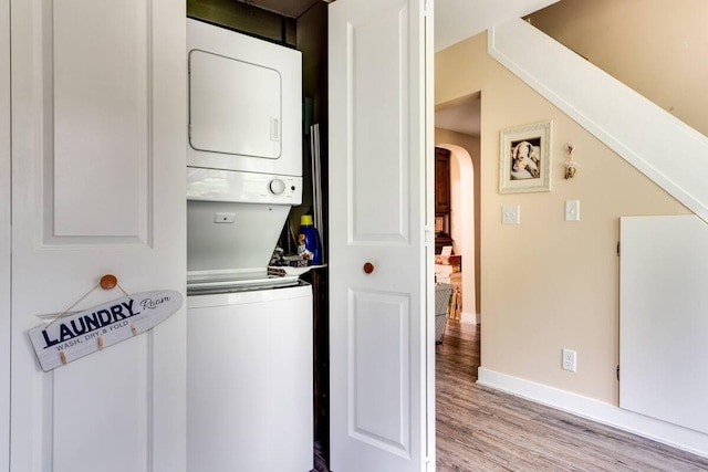 2085 Queens Ave S, Lakeland, MN 55043 - washroom featuring laundry area, stacked washer and dryer, arched walkways, baseboards, and light wood-style flooring