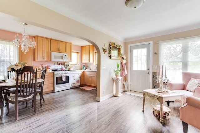 2085 Queens Ave S, Lakeland, MN 55043 - kitchen with light brown cabinetry, arched walkways, light countertops, white appliances, and light wood-style flooring