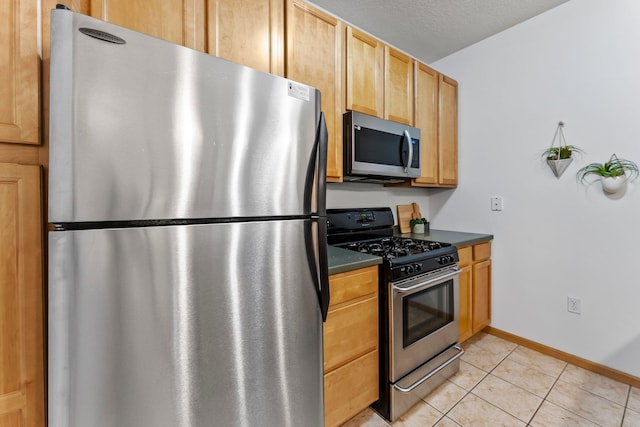 2565 Franklin Ave Unit 109, Saint Paul, MN 55114 - kitchen featuring appliances with stainless steel finishes, dark countertops, light tile patterned floors, baseboards, and a textured ceiling