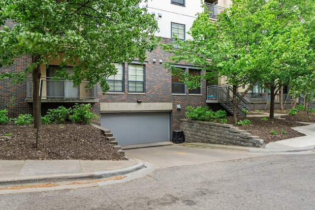 2565 Franklin Ave Unit 109, Saint Paul, MN 55114 - view of front of house with brick siding, a garage, concrete driveway, and stairway