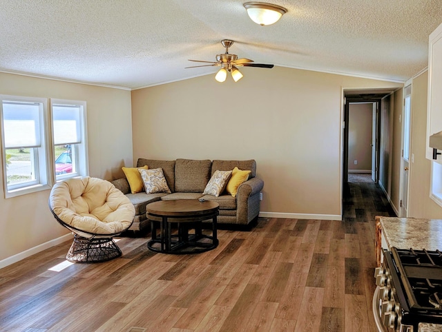 living area with vaulted ceiling, wood finished floors, a textured ceiling, and ceiling fan