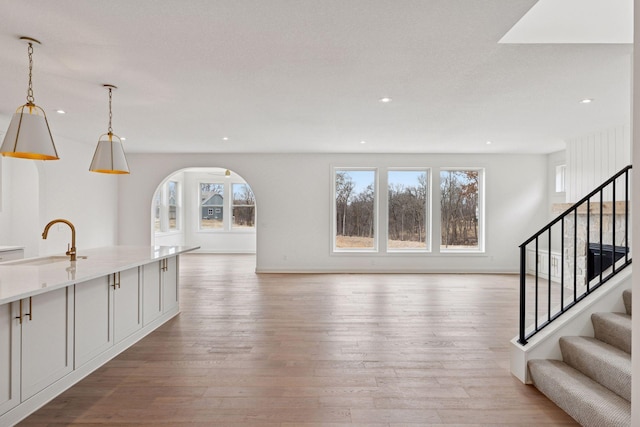 6200 Harkness Alcove S, Cottage Grove, MN 55016 - unfurnished living room with plenty of natural light, arched walkways, light wood-style flooring, and recessed lighting