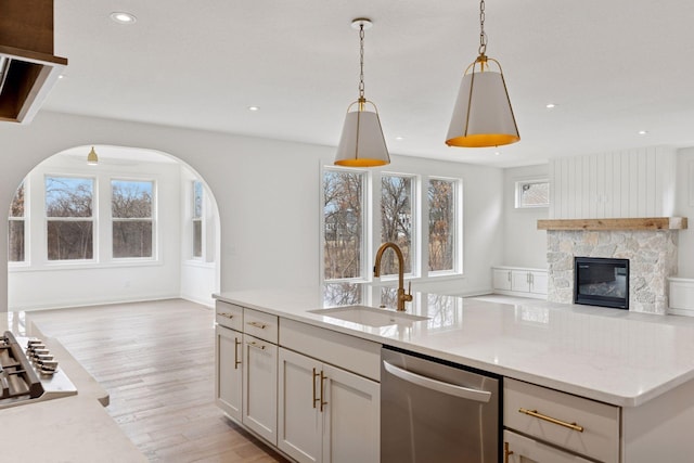 6200 Harkness Alcove S, Cottage Grove, MN 55016 - kitchen featuring appliances with stainless steel finishes, open floor plan, arched walkways, light wood-type flooring, and a stone fireplace