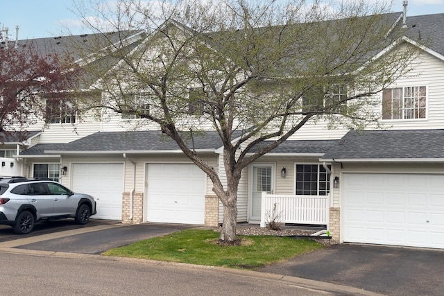 traditional-style house featuring driveway, roof with shingles, and a garage