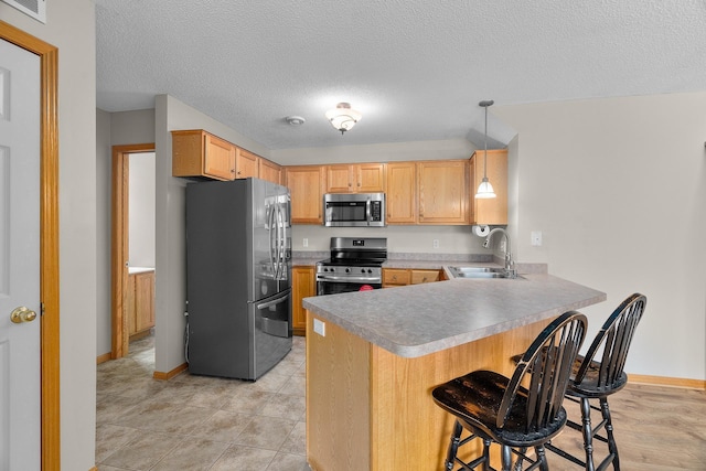 kitchen featuring a sink, a peninsula, stainless steel appliances, baseboards, and visible vents