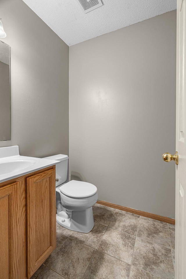 bathroom featuring toilet, vanity, a textured ceiling, and visible vents