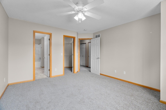 unfurnished bedroom featuring baseboards, visible vents, carpet floors, and a walk in closet