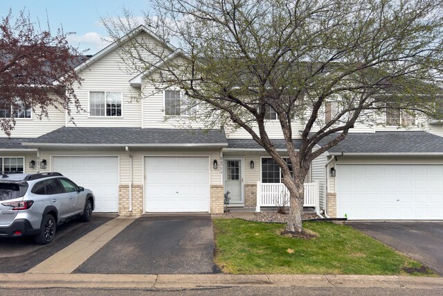 traditional-style home with brick siding, an attached garage, driveway, and roof with shingles