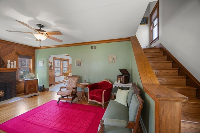 1114 6th St, Mankato, MN 56001 - living room featuring ornamental molding, wood finished floors, a brick fireplace, a ceiling fan, and arched walkways