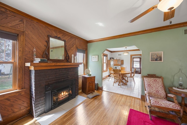 1114 6th St, Mankato, MN 56001 - living room featuring arched walkways, ornamental molding, plenty of natural light, a brick fireplace, and light wood finished floors