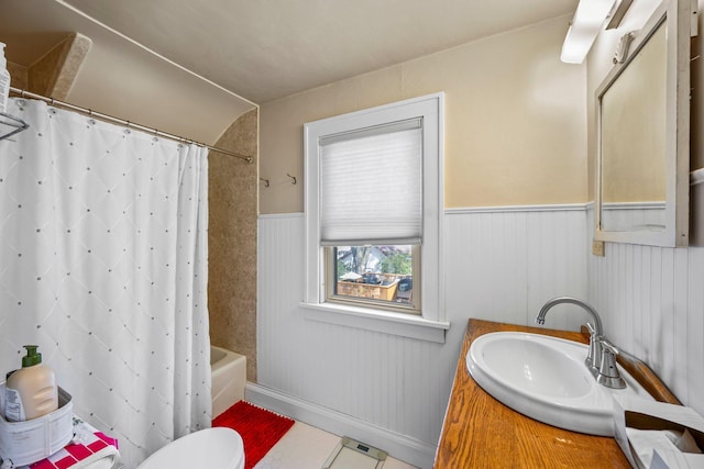 1114 6th St, Mankato, MN 56001 - bathroom with shower / tub combo with curtain, a wainscoted wall, vanity, tile patterned floors, and toilet