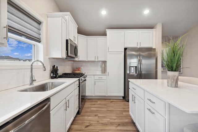 1905 Arbor Ln, Carver, MN 55315 - kitchen featuring stainless steel appliances, light wood-style floors, a sink, white cabinetry, and recessed lighting