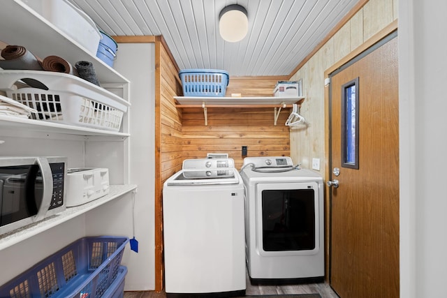clothes washing area featuring washer and dryer, wooden walls, and laundry area