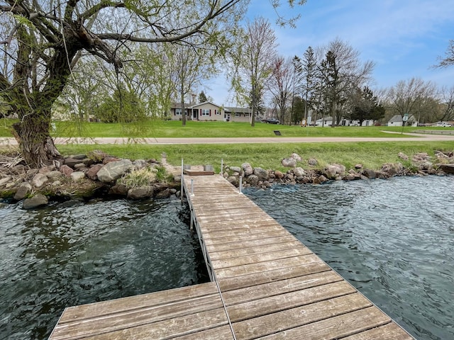 view of dock featuring a lawn and a water view