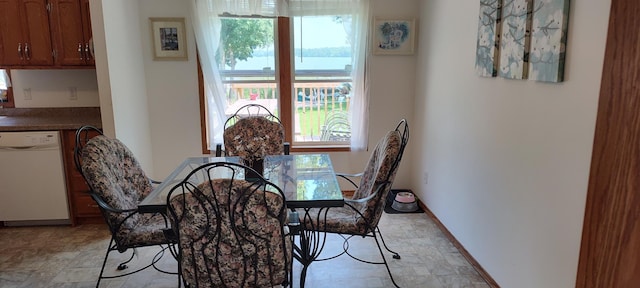 dining space featuring a healthy amount of sunlight, stone finish flooring, and baseboards